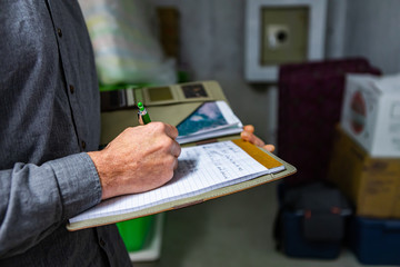 inspector holding a notebook in his hand during a home inspection in the basement, Close up and...
