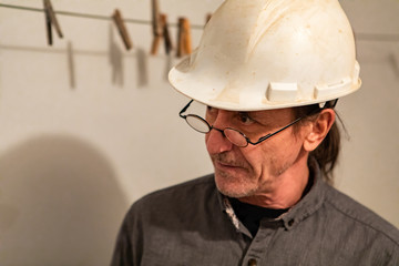 portrait of an inspector wearing small glasses and white helmet, middle aged man face and head in close up side view with copy space