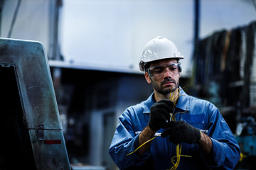 staff engineer male employee at a factory plant operating a production line machine and setting it...