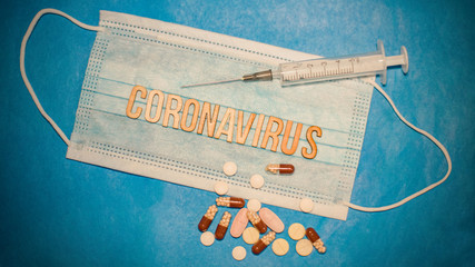 Novel Coronavirus outbreak concept. Coronavirus protective breathing mask and syringe over scattered tablets and ukrainian flag. 2019 nCoV virus infection originating in Wuhan, China...