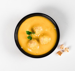 Pumpkin puree soup with chicken meatballs in a bowl on a light background
