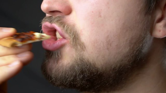 A young man eats pizza slow motion super close up profile