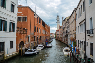 Boats aligned on narrow venice channel bounded by ancient buildings, Venice, Italy