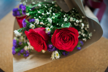 bouquet of roses arrangements of flowers in a paper wrapper on wooden background