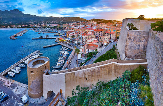 View from the walls of the citadel of Calvi on the old town with historic buildings at evening sunset. Bay with yachts and boats. Luxurious marina popular tourist destination. Corsica, France.