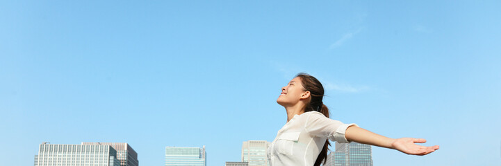 Happy woman with open arms in city sky panoramic banner breathing clean air for pollution concept...
