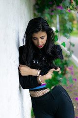 pretty Colombian woman lying on a white wall in a garden