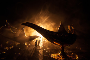 Silhouette of a man standing in the middle of the road on a misty night with giant Antique Aladdin arabian nights genie style oil lamp. Creative artwork decoration © zef art