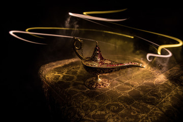 Lamp of wishes concept. Antique Aladdin arabian nights genie style oil lamp with soft light white...