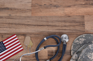 Military and Veterans Health Care Concept. Dog tags, American Flag, military camo hat and stethoscope on a wood background.