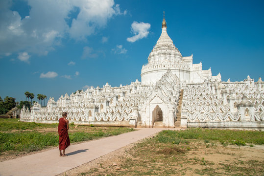 Burmese monk standing in front of Hsinbyume pagoda other name called 'Taj Mahal of Irrawaddy river'. This pagoda representing Mount Meru of Buddhist cosmology located in Sagaing region of Myanmar.