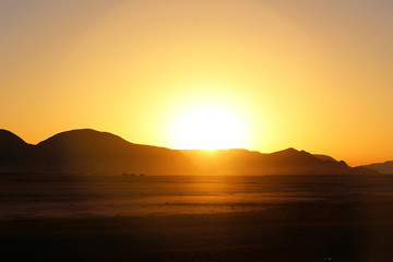 Fototapeta premium sunset against mountain in desert with camels