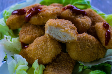 primer plano de nugget de pollo mordido sobre lechuga y salsa de tomate arriba 