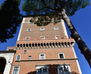 Palazzo Venezia at Piazza Venezia with blue sky. Tower close-up, perspective from below. Rome, Italy.