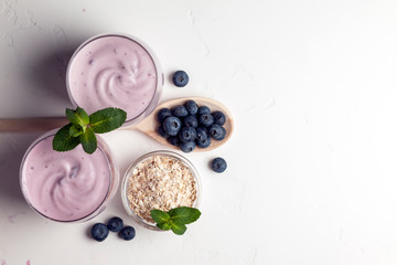 two fresh blueberry yogurt with blueberries on a white texture table, top view