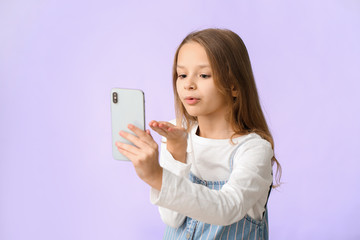 Cute little girl taking selfie on color background