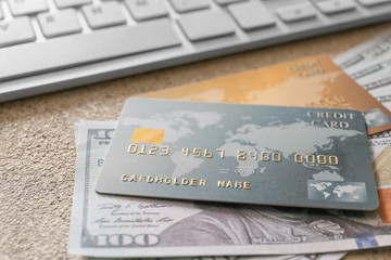 Credit cards with money and computer keyboard on grey background, closeup. Concept of online banking