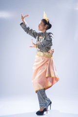 A beautiful Malaysian traditional female dancer performing a cultural dance routine in a traditional outfit on a stage. Full length portrait.