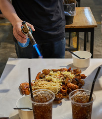 Chef is preparing food with a bunsen burner direct at the    table on a night market in Bangkok, Thailand