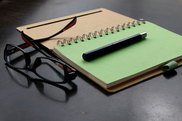 Notebook, pen and eyeglasses on a table