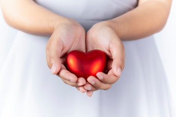 Female hands holding red heart in hands, giving heart, valentine day, closeup.