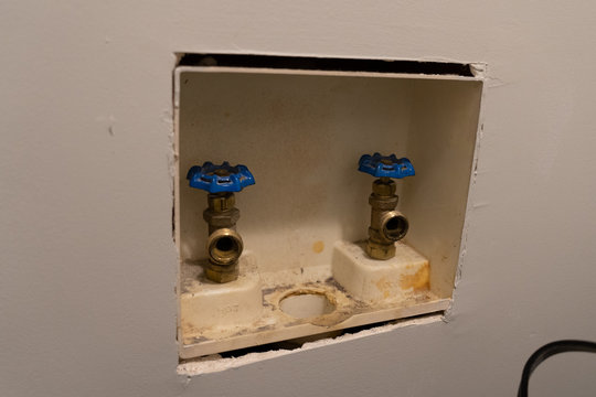 Washing machine plumbing hook-up for water supply and drain in a laundry room.