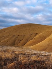 The golden light of sunrise strikes the unique Painted Hills in the John Day Fossil Beds National Monument in Eastern Oregon on a cold winter morning.