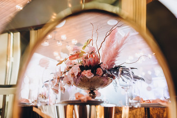 Wedding decorations. Festive table decorated with compositions of colored flowers. On the tables are plates, glasses, candles and cutlery