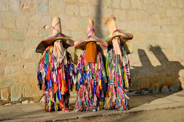 Three traditional Tiliche costume against wall in Oaxaca, Mexico