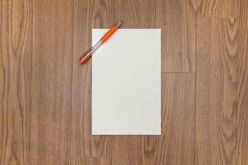 A orange ballpoint pen and Blank note paper on the floor.