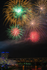 Obraz premium fireworks against a black sky background over a river and a bridge.