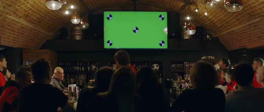 WIDE FIXED Model Released, Fans Watching A Game On A Large TV In A Sport Pub, Green Screen Chroma Key With Tracking Points. Shot On ARRI Alexa Mini With Atlas Orion 2x Anamorphic Lens