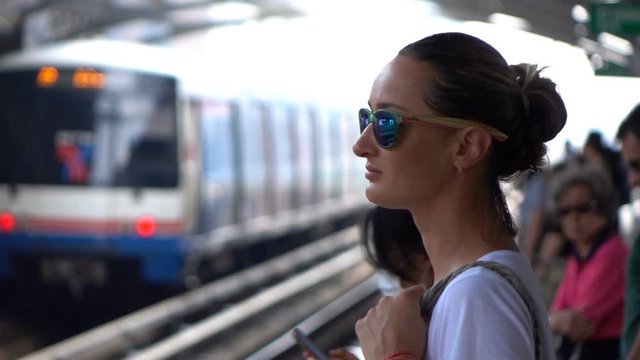 Beautiful young woman waiting for a train on station, slow motion
