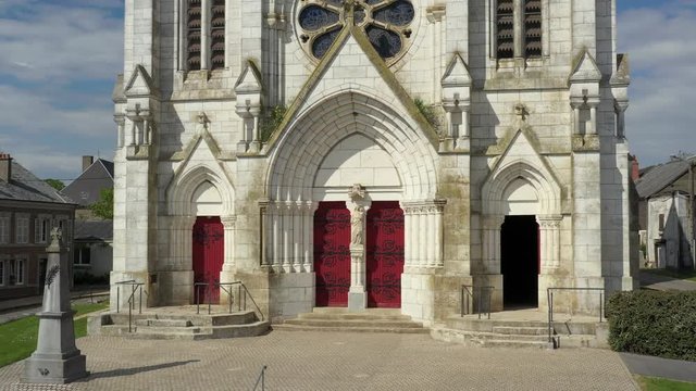 Breathaking Gothic style church with beautiful red doors in a small French village,Neuvizy.  drone dolly away.