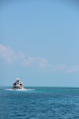 Sport fishing boat in distance cruising away from camera in blue tropical water