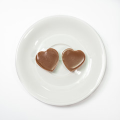 The close up of Love heart shape chocolate on coffee cup plate on white background.