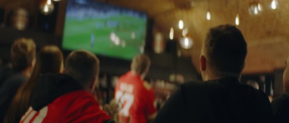 HANDHELD Model released, fans watching a game on a large TV in a sport pub. Shot on ARRI Alexa Mini with Atlas Orion 2x Anamorphic lens