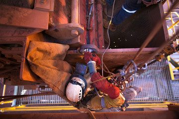 Rope access welder hanging on rope working at height in fall arrest position performing using die...
