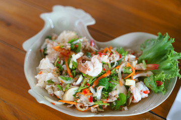 Eating Thai seafood spicy salad with shrimp and pork