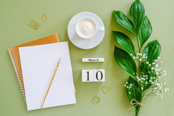 Wooden cubes calendar March 10. Open blank notepad, cup of coffee, bouquet flowers on green background. Concept hello spring Creative Top view Flat lay Mock up.