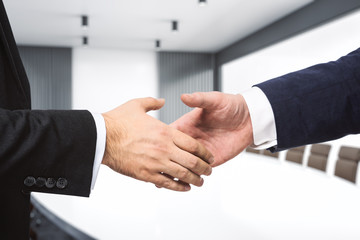 Obraz premium Two businessmen shake hands in a meeting room, closeup