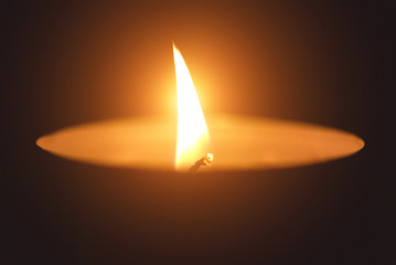 Burning candle in the dark close up background.