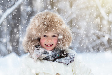 Child playing with snow in winter. Kids outdoors.