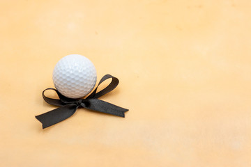 Golf ball with black ribbon on light background
