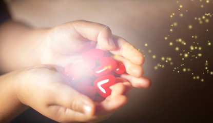 光を放つ沢山の赤いハートのモチーフを持つ子供の手