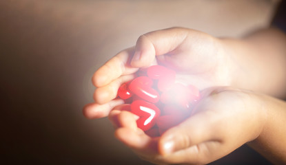 光を放つ沢山の赤いハートのモチーフを持つ子供の手