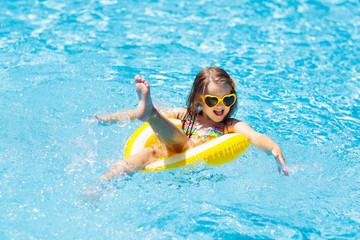Child in swimming pool on ring toy. Kids swim.