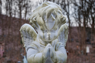Naklejka premium Old stone angel on a forest background (religion, faith concept)
