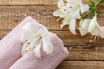 Soft terry towels with bouquet of flowers on wooden background.