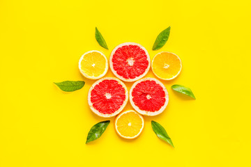 Citrus pattern. Lemon and grapefruits slices and leaves on yellow background top-down